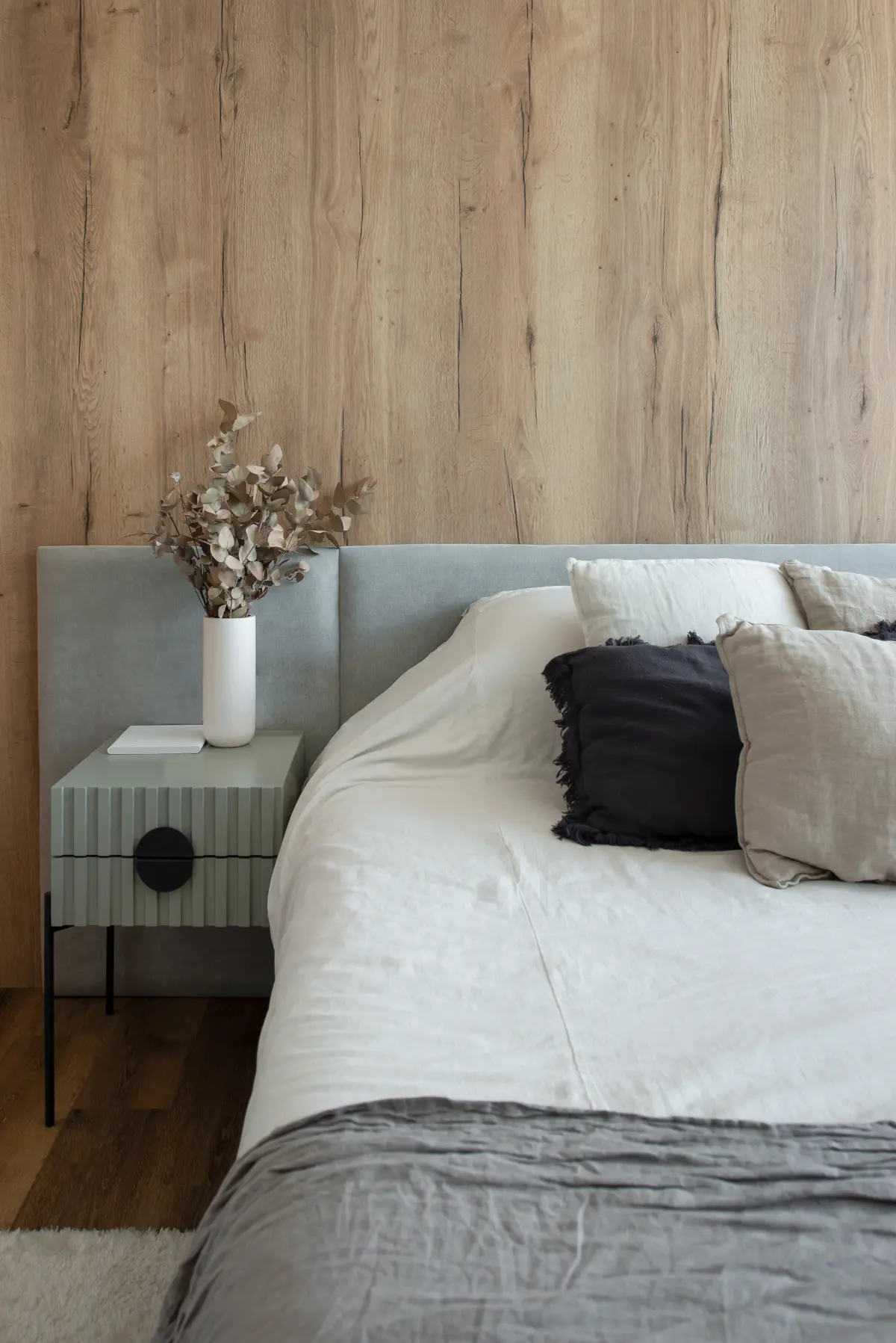 Dormitorio moderno con pared de madera, cama blanca y mesa de noche de rayas — proyecto Depto Arribeños, por Ayelen Mayer Arquitectura, en Buenos Aires